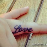 Фото минималистичной татуировки с надписью 'Love', выполненной черными чернилами на пальце руки.