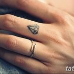 Фото тату маленького черного бриллианта на безымянном пальце руки. Минималистичный рисунок татуировки, выполненный тонкими линиями, идеально подходит для девушек.