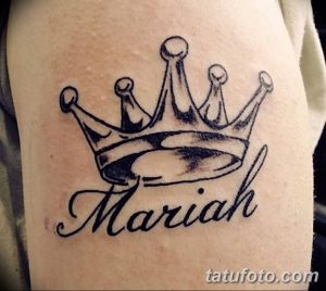 Фото тату на предплечье: черная корона над именем 'Mariah', выполненная в классическом стиле. Изящный рисунок татуировки для девушек.