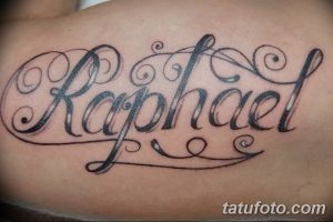 Фото тату на спине: имя 'Raphael', написанное красивым каллиграфическим шрифтом с декоративными элементами.