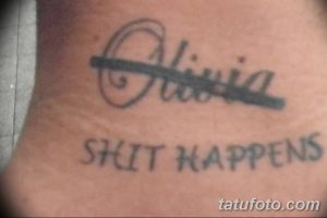 Фотография татуировки с именем 'Olivia' в декоративной рамке и надписью 'Shit Happens' под ней. Татуировка выполнена черным цветом.
