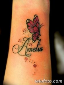 Фото тату с изображением бабочки и имени 'Amelia', украшенных маленькими звездами. Черно-красная татуировка, нежный дизайн, женский стиль.