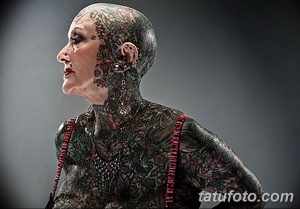 Фотография женщины в возрасте, чье тело полностью покрыто сложными и красочными татуировками.