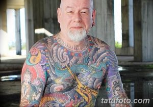 Фото тату на теле пожилого мужчины, покрытого яркими и красочными рисунками. Татуировки выполнены в японском стиле и изображают драконов и других мифологических существ.