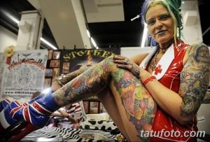 Фото тату: женщина, полностью покрытая яркими татуировками, позирует на тату-конвенции. Многообразие стилей и цветов.