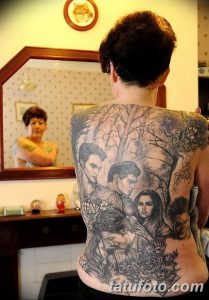 Фото масштабной татуировки на спине мужчины, изображающей сцену с персонажами и деревьями в черно-белом стиле.