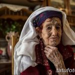 Фото пожилой женщины с морщинистым лицом и татуировками на руках, демонстрирующее ее жизненный опыт и индивидуальность.