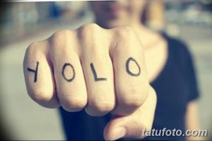 Фото тату: надпись YOLO (You Only Live Once) на костяшках пальцев, выполненная черными чернилами, минималистичный и дерзкий дизайн.