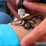 Фото тату: процесс нанесения мехенди – временной татуировки хной, на кожу руки. Виден аппликатор с хной и начальный этап рисунка.
