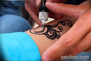 Фото тату: процесс нанесения мехенди – временной татуировки хной, на кожу руки. Виден аппликатор с хной и начальный этап рисунка.