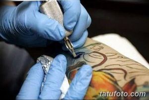 Фото процесса татуировки: мастер в перчатках наносит рисунок на кожу с помощью тату-машинки. Детализированное фото тату.