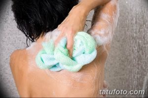 Фотография девушки, принимающей душ и использующей мочалку для тела. Идеально для иллюстрации гигиены и ухода за собой.