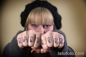 Фото татуировки надписи 'Lady Luck' на костяшках пальцев. Черный цвет, дерзкий стиль.