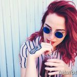 Фотография девушки с татуировкой на руке. Девушка пьет напиток через трубочку и смотрит в камеру.
