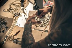 Фото процесса создания эскиза татуировки. Мастер тату рисует сложный орнамент на бумаге, используя карандаш и другие инструменты.
