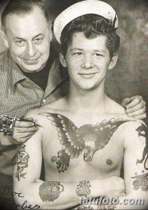 Старинная фотография, изображающая тату-мастера, делающего татуировку орла на груди моряка. Видны другие татуировки на теле моряка.