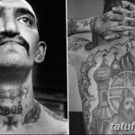Фотография мужчины с тюремными татуировками на лице и теле. Рисунки выполнены в черно-белом стиле и имеют символическое значение.