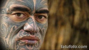 Фотография мужчины с татуировками в стиле маори на лице. Рисунок детализированный и занимает большую площадь.
