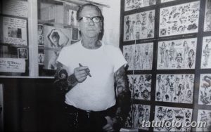 Фотография старого мастера тату в его студии, окруженного эскизами и работами. Изображение демонстрирует атмосферу тату-индустрии прошлых лет.
