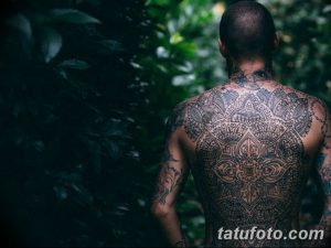 Фотография мужской спины, полностью покрытой сложной и детализированной татуировкой в стиле мандала, демонстрирующей симметрию и духовность.