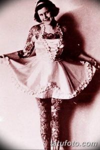 Старинное фото женщины, полностью покрытой татуировками. Руки, ноги и тело украшены сложными рисунками, демонстрирующими искусство татуирования начала 20 века.