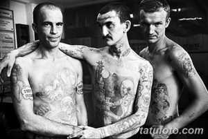 Чёрно-белое портретное фото трёх мужчин с тюремными татуировками. Видны рисунки на руках, шее и груди, отражающие их прошлое.
