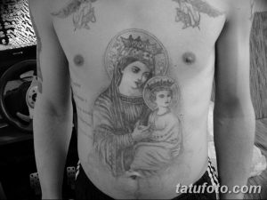 Фотография татуировки на груди мужчины, изображающей Деву Марию с младенцем Иисусом. Татуировка выполнена в реалистичном стиле.