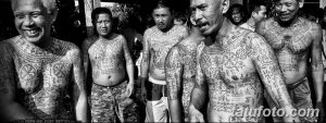 Фотография группы мужчин с традиционными тайскими татуировками, покрывающими их тела. Черно-белое изображение демонстрирует сложные узоры и символы.