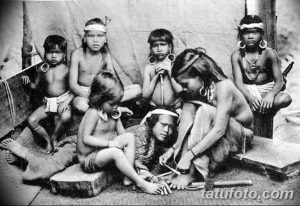 Фотография, изображающая процесс традиционного татуирования у коренных народов. Видны люди, выполняющие татуировки друг другу с использованием примитивных инструментов.