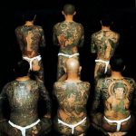 Фотография шести мужчин с полностью татуированными спинами в японском стиле Ирэдзуми. Изображены мифические существа, цветы и сложные узоры.