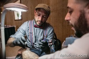 Фото мастера тату, делающего татуировку клиенту во время свадебной церемонии. Профессиональный подход и индивидуальный дизайн.