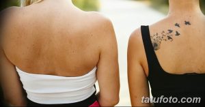 Фото татуировки на спине девушки, изображающей одуванчик, из которого вылетают птицы, выполненной в черном цвете с использованием тонких линий.