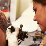 Фотография процесса нанесения татуировки на плечо девушки, мастер работает тату-машинкой.