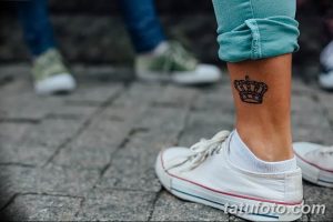 Фото тату: маленькая черная татуировка в виде короны на лодыжке девушки, выполненная в минималистичном стиле.