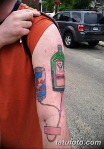 Фото тату на предплечье: бутылка Jägermeister и банка Red Bull соединенные трубкой. Юмористический рисунок татуировки для любителей напитков.