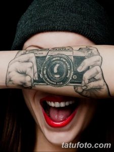 Фото тату фотоаппарата на руке, создающего иллюзию, будто камера держит человека в фокусе. Оригинальный и креативный дизайн.
