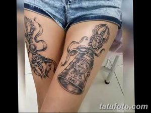 Фото тату: две симметричные татуировки на бедрах, изображающие традиционные восточные сосуды с лицами божеств, выполненные в черном цвете.