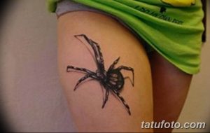 Фотография татуировки черного паука на бедре девушки. Детализированный рисунок с реалистичными лапами.