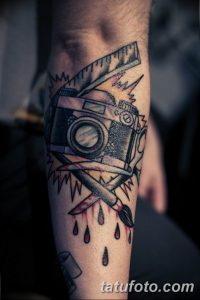 Фотография татуировки на предплечье с изображением фотоаппарата, кистей, красок и других художественных инструментов. Рисунок выполнен в ярком и красочном стиле.