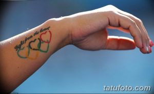 Фото тату олимпийских колец и надписи 'Fight from the heart' на запястье, символизирующее спортивный дух и мотивацию.