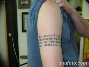 Фото тату: Черный рисунок кодировки US-ASCII/UTF-8 на плече мужчины. Детализированный эскиз татуировки, выполненный тонкими линиями.