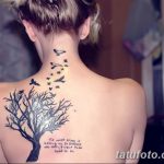 Фото тату с изображением дерева жизни, летящих птиц и вдохновляющей цитаты, выполненное в черном цвете.