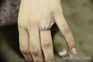 Фото тату: небольшая татуировка с надписью "Aakash" на пальце руки. Простой и стильный рисунок татуировки.