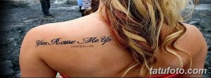Фото тату надпись на лопатке. Черная надпись "You Raise Me Up" на спине девушки.