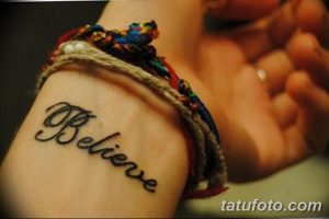 Фото татуировки с надписью "Believe" на запястье девушки. Черно-белый рисунок татуировки выполнен красивым каллиграфическим шрифтом.