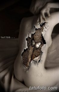 Фото тату совы, словно вырывающейся из-под кожи на спине девушки. Реалистичный рисунок с использованием коричневых и серых оттенков.