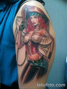 Фото тату: Красочная татуировка на плече, изображающая девушку-пиратку с пистолетом. Детализированный рисунок и яркие цвета.