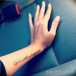 Фото татуировки на запястье с надписью "God is still working on me". Тонкий шрифт и минималистичный дизайн.