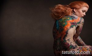 Фото тату: Большая и яркая татуировка павлина на спине девушки. Детализированный рисунок татуировки с использованием множества цветов и оттенков.