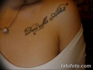 Фото тату: Надпись "Dane Me Alas" в каллиграфическом стиле, выполненная на ключице девушки. Элегантный рисунок татуировки с красивым шрифтом.